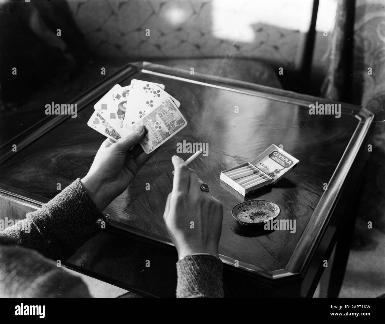 Pubblicità Fotografia UNA donna che gioca carta e fuma una sigaretta Data: Parole Chiave dense: Giochi di carte, sigarette Foto Stock