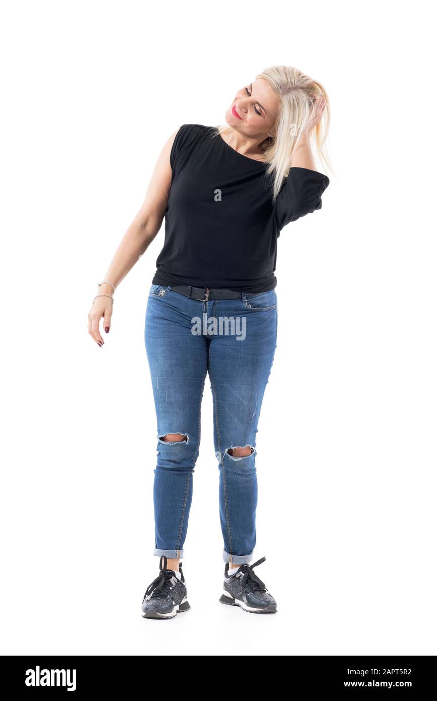 Felice spensierato casual signora di mezza età rilassante e sorridente toccando i capelli con la mano. Corpo intero isolato su sfondo bianco. Foto Stock