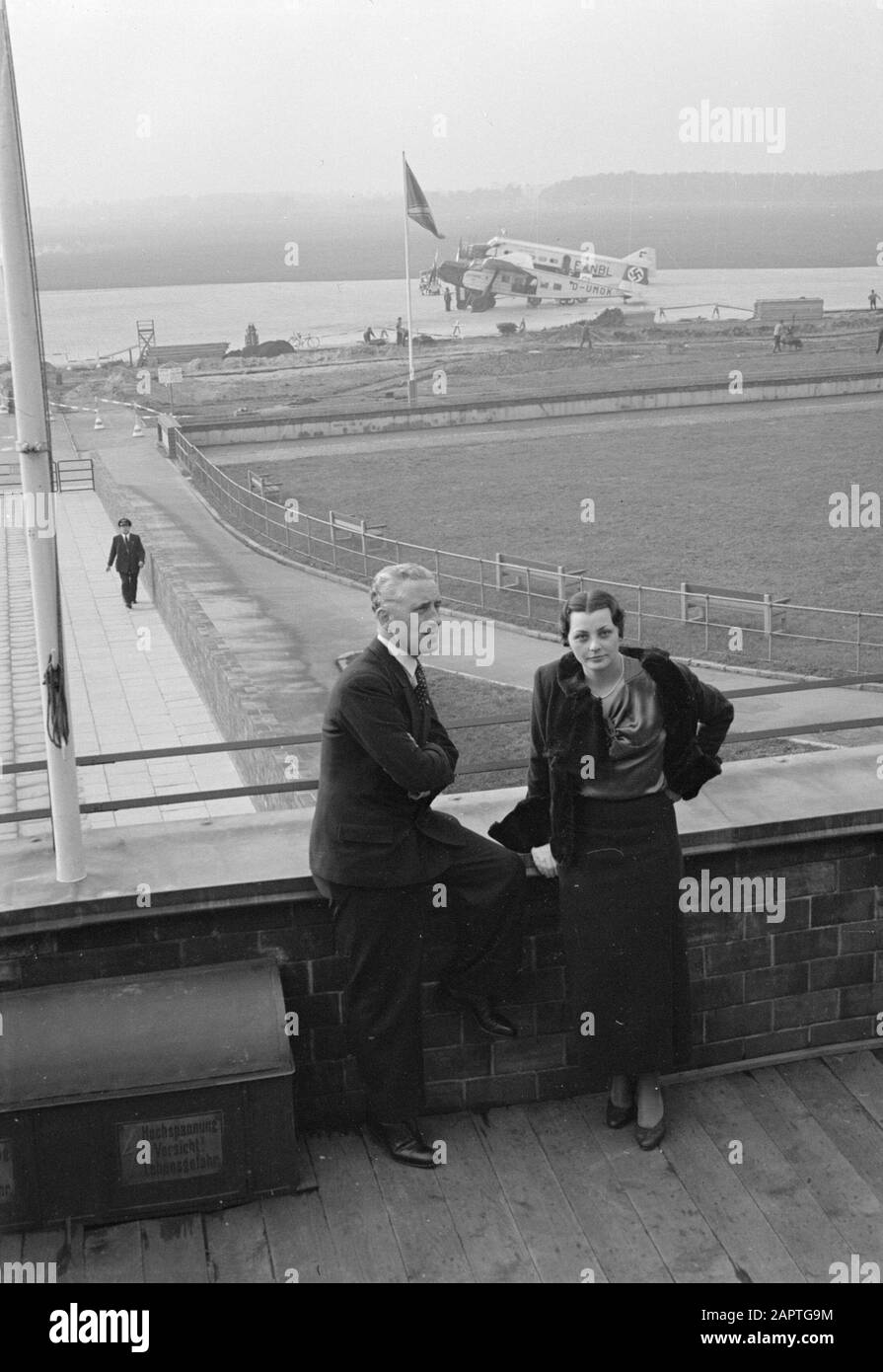 Aeroporto di Amburgo Harry Laponder con una donna sconosciuta sulla terrazza dell'edificio dell'aeroporto con in background un BFW M.20 D-UMOK e un Wibault 280.T F-ANBL Data: 13 agosto 1934 posizione: Germania, Amburgo Parole Chiave: Visitatori, aviazione, compagnie aeree, terrazze, aeromobili, personale aereo, aeroporti Nome personale: Laponder, Harry Foto Stock