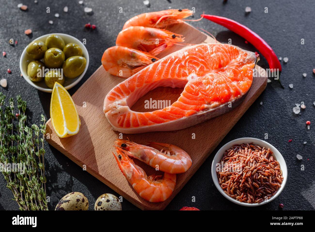 Trote crude bistecca di pesce rosso servito con erbe e limone e olio d'oliva su uno sfondo scuro. Cucina salmone, frutti di mare. Concetto di alimentazione sana Foto Stock