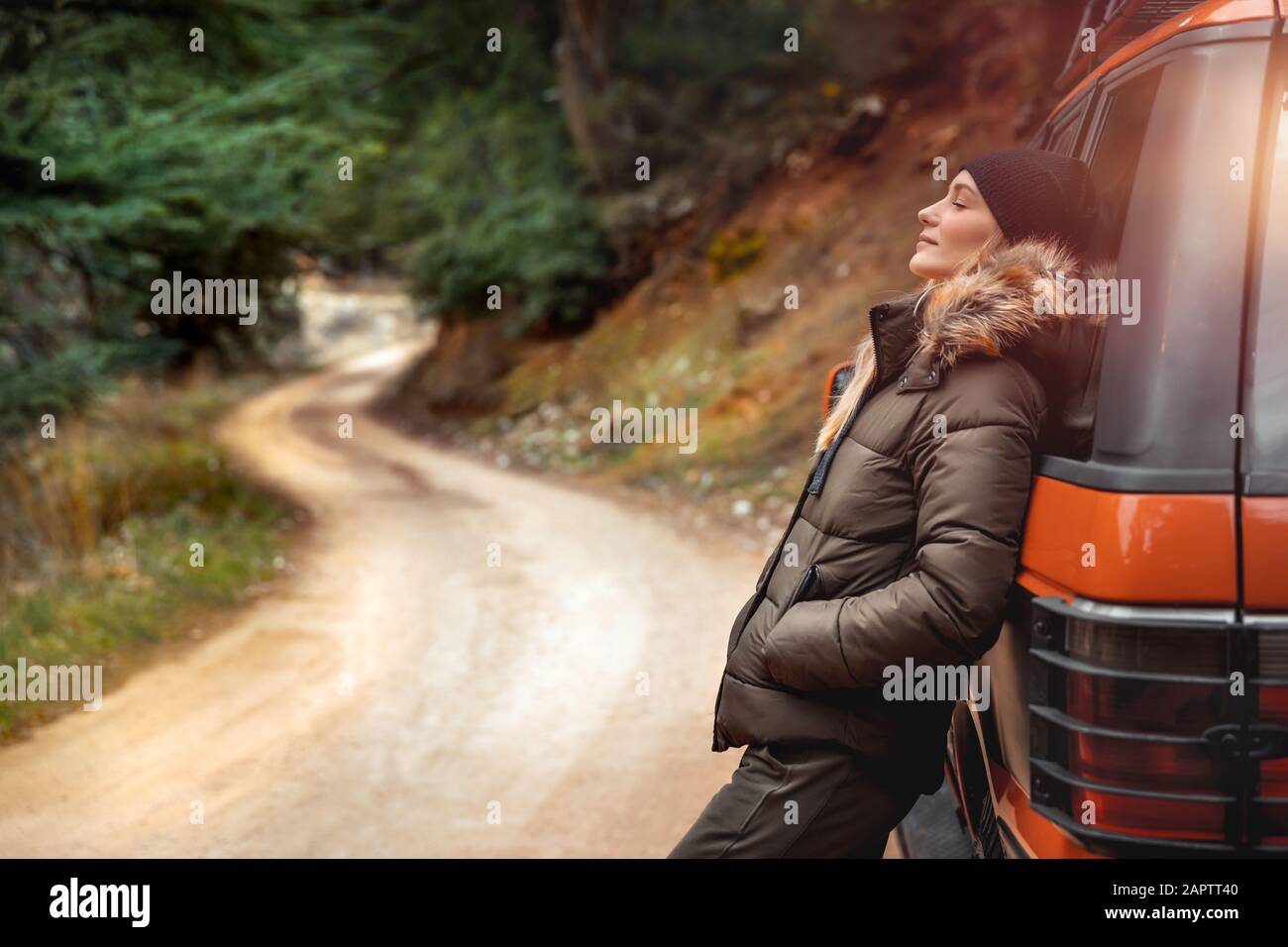 Godendo di un silenzio montuoso, bella donna appoggiata su una macchina e gode della natura con occhi chiusi, viaggio fuoristrada, week-end attivo, felice vita Foto Stock