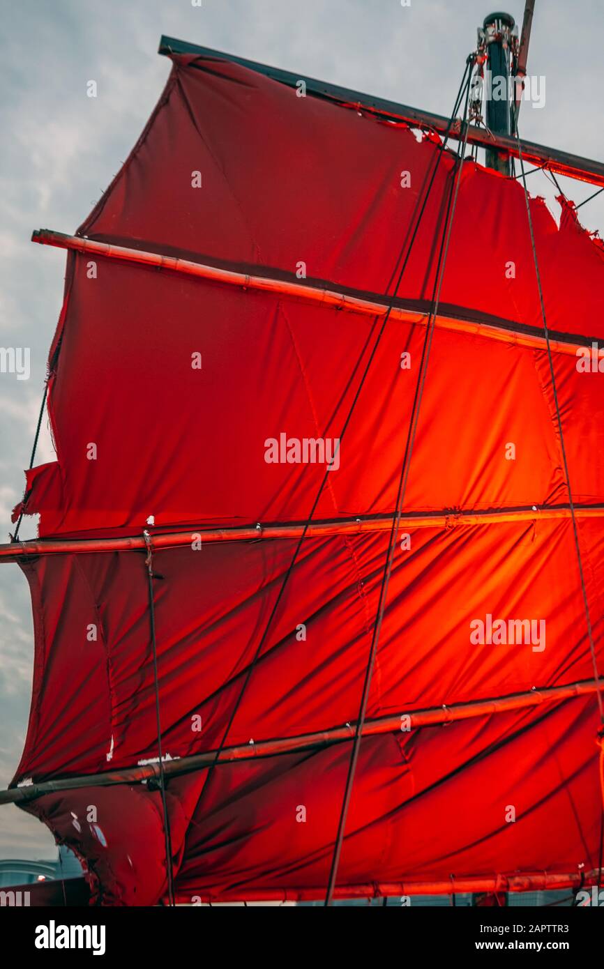 Barca spazzatura con vela rossa a Hong Kong. Punto di riferimento locale e il porto Victoria sullo sfondo. Foto Stock