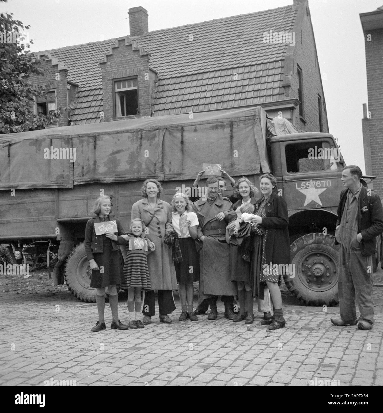 Liberazione del Brabante Nord lungo il corridoio Bergeijk - Valkenswaard - Aalst - Eindhoven Residenti di Aalst in posa con un militare delle guardie irlandesi; in mano bandiere inglesi e americane di carta Data: 18 settembre 1944 Località: Aalst, Noord-Brabant Parole Chiave: Liberazione, cittadini, villaggi, ritratti di gruppo, soldati, bandiere, camion Foto Stock
