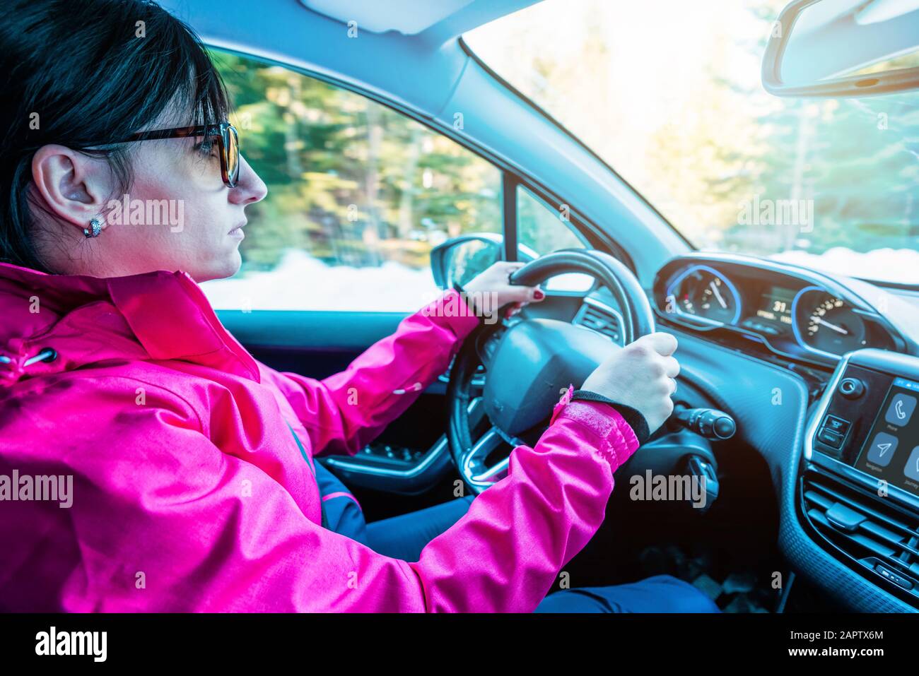 La ragazza nella giacca guida l'auto. Interni moderni. Concetto di sicurezza durante la guida invernale Foto Stock