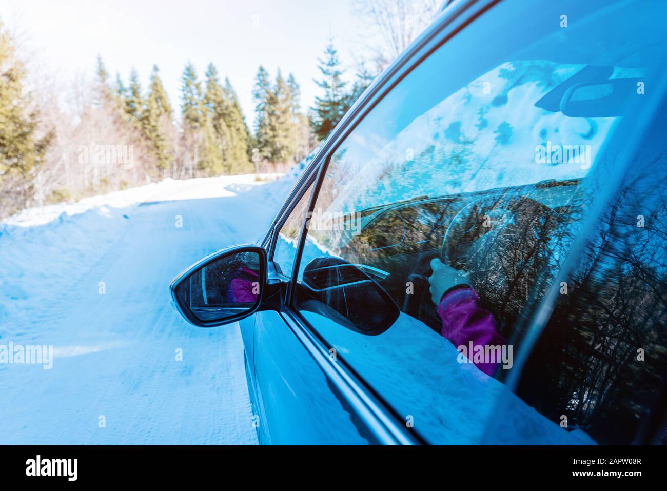 Vista dello specchietto retrovisore di un'auto in movimento su una superficie innevata invernale. Concetto di guida sicura in condizioni invernali Foto Stock
