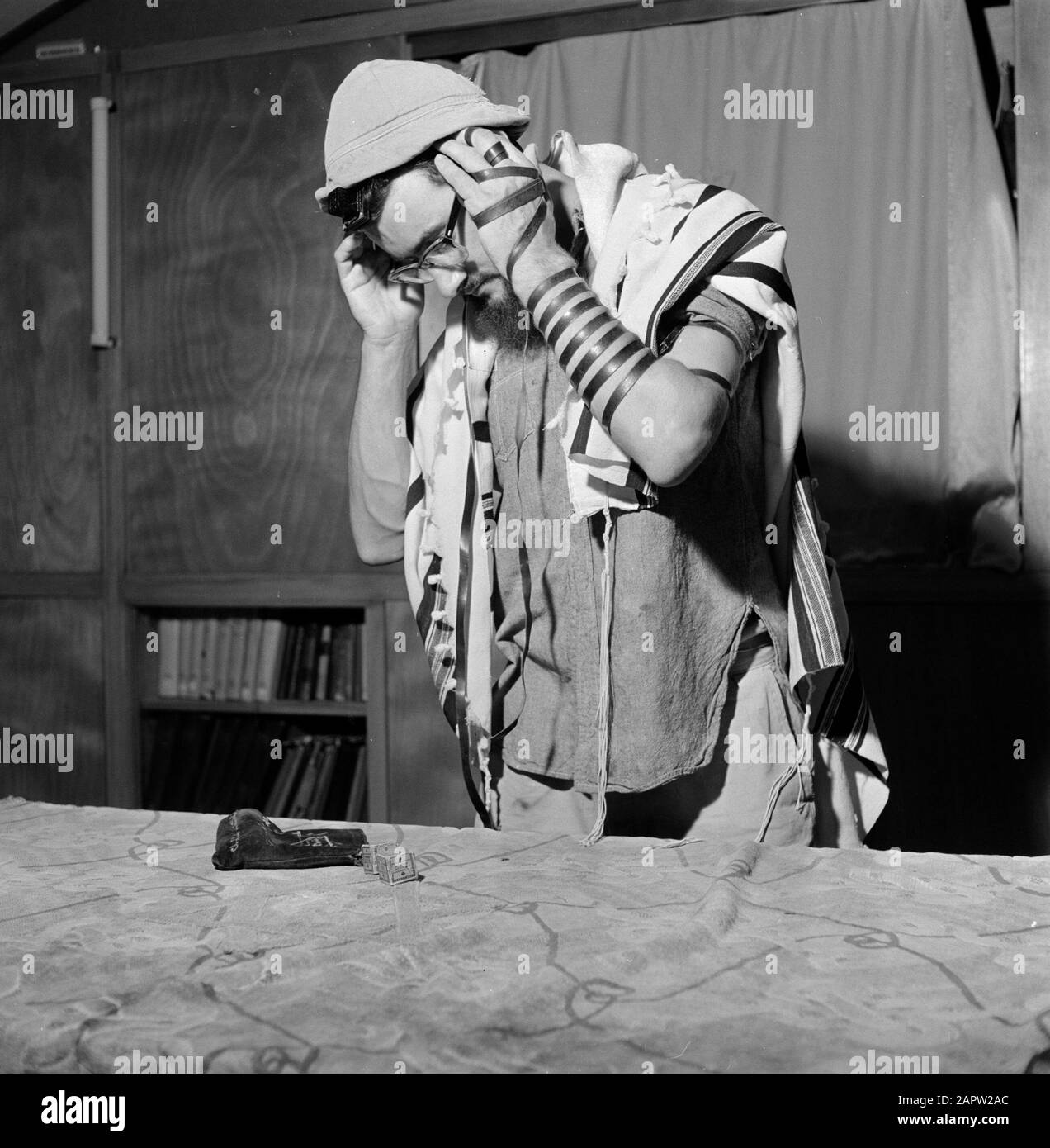 Uomo ebraico con un cappello e un mantello di preghiera da impegnarsi nella posa di cinture di preghiera (tefelin) Data: 1 gennaio 1963 luogo: Israele Parole Chiave: Preghiere, cappelli, religione ebraica, riti Foto Stock