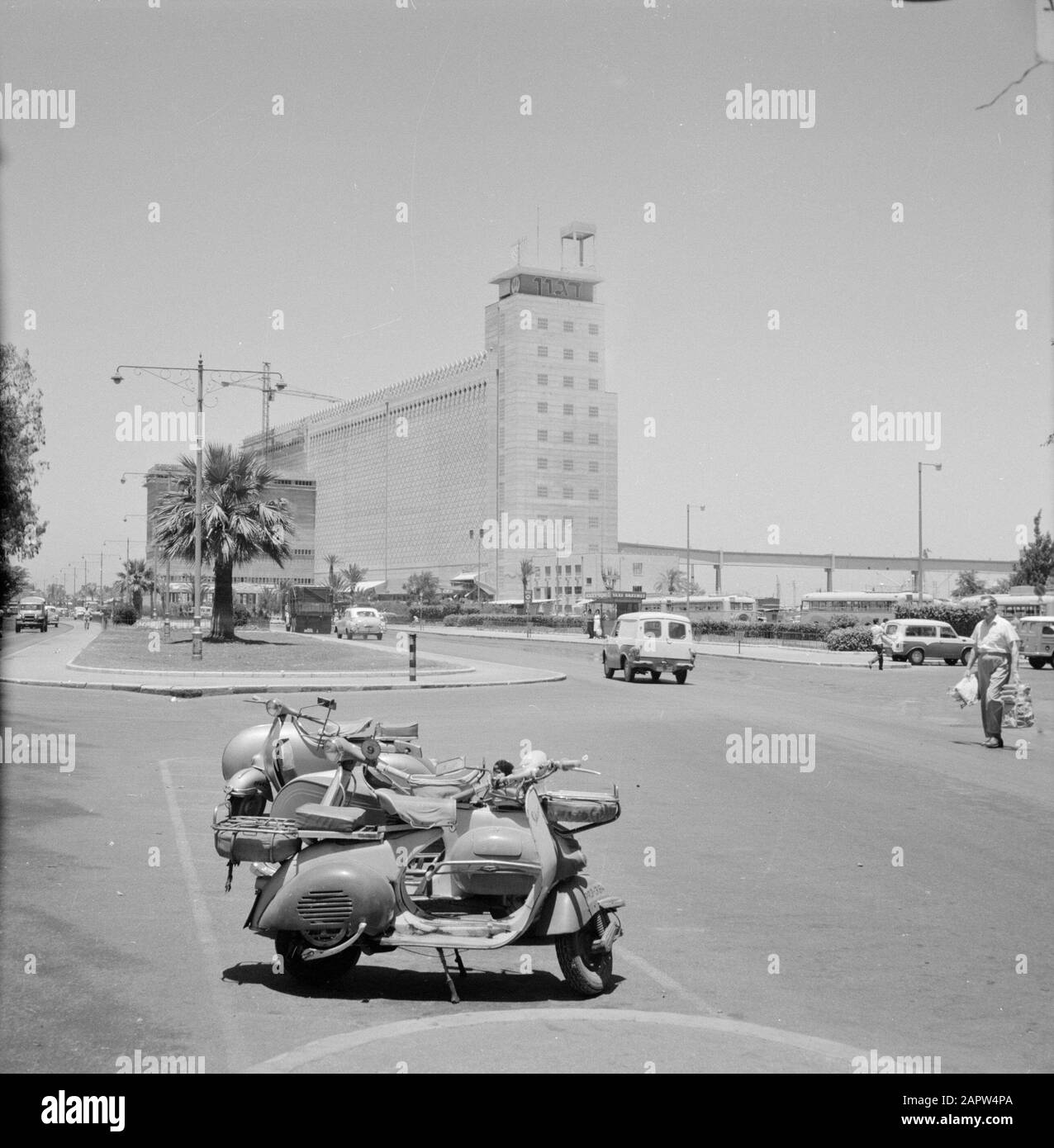 Israele 1964-1965: Haifa, silo di grano Edificio Caratteristico; 'silo di grano di agon' Annotazione: Ciclomotori parcheggiati in primo piano lungo la strada Data: 1964 Località: Haifa, Israele Parole Chiave: Automobili, ciclomotori, silos, pedoni, strade Foto Stock