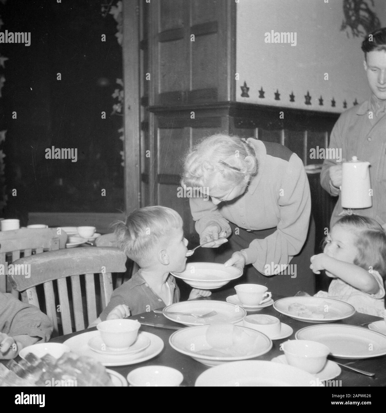 Reportage i bambini marini mangiano ad un tavolo. Ragazzo è alimentato da donna anziana Data: Non ha dato Foto Stock