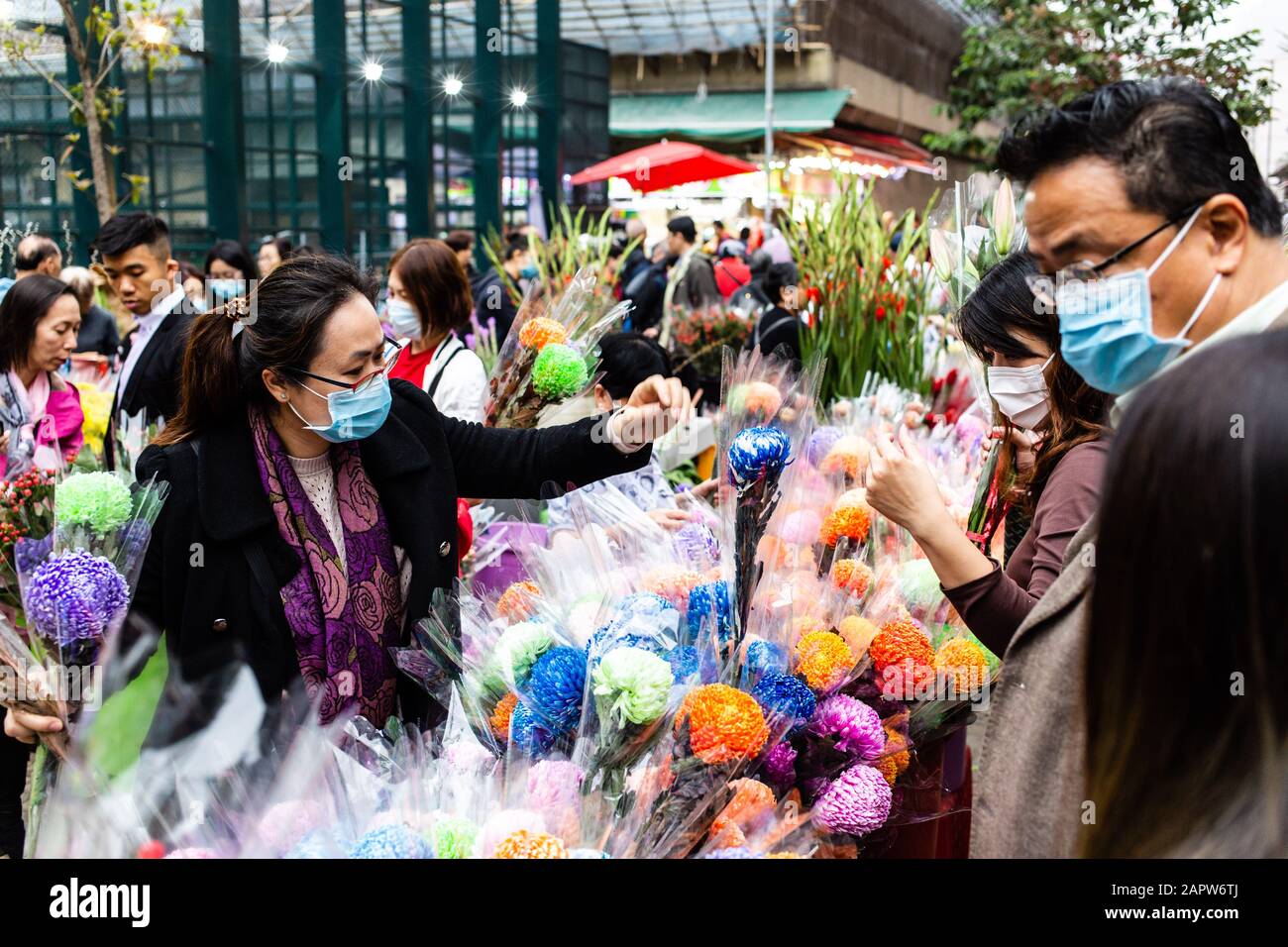 Le famiglie acquistano fiori per il Lunar New Year Celebrations.Alla luce di un'epidemia mortale di virus in Cina, i cittadini di Hong Kong indossavano maschere chirurgiche nel timore di contrarre l'influenza. Con le vacanze Lunar di Capodanno dietro l'angolo, molti cittadini stanno annullando i viaggi in Cina e procedendo con cautela. Foto Stock