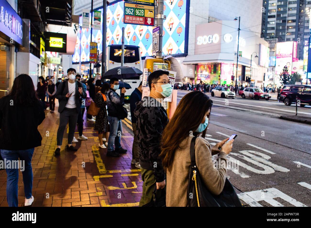 La gente ad una fermata dell'autobus porta maschere chirurgiche.alla luce di un focolaio mortale del virus in Cina, i cittadini di Hong Kong indossavano maschere chirurgiche nel timore di contrarre l'influenza. Con le vacanze Lunar di Capodanno dietro l'angolo, molti cittadini stanno annullando i viaggi in Cina e procedendo con cautela. Foto Stock