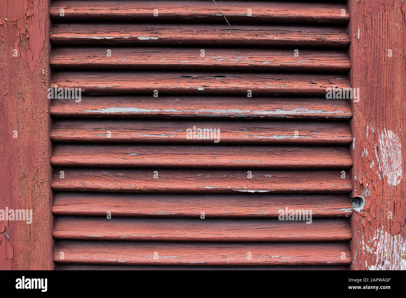 Primo piano di un vecchio otturatore in legno rosso sporco con pelatura della vernice rovinato e rovinato Foto Stock