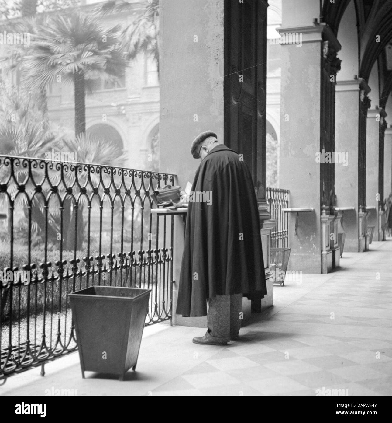 Roma: Visita alla città l'uomo a tavola in una delle colonne nella galleria di un antico monastero dove si trova ora un ufficio postale Data: Dicembre 1937 Località: Italia, Roma Parole Chiave: Monasteri, monasteri, pilastri, uffici postali, giardini Foto Stock