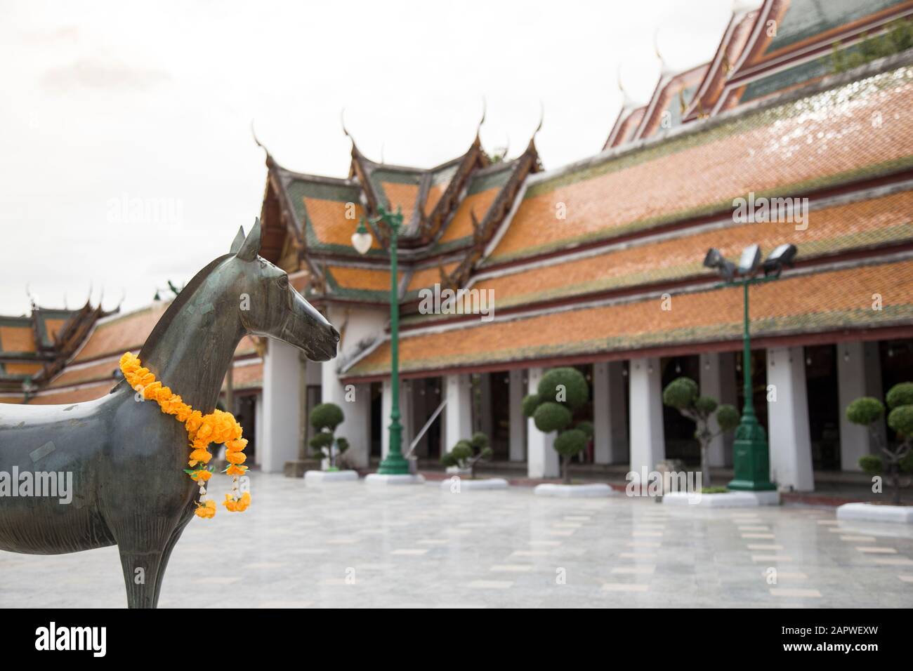 Statua di bronzo con un ghirlande di fiori a Wat Suthat Thepwararam Foto Stock