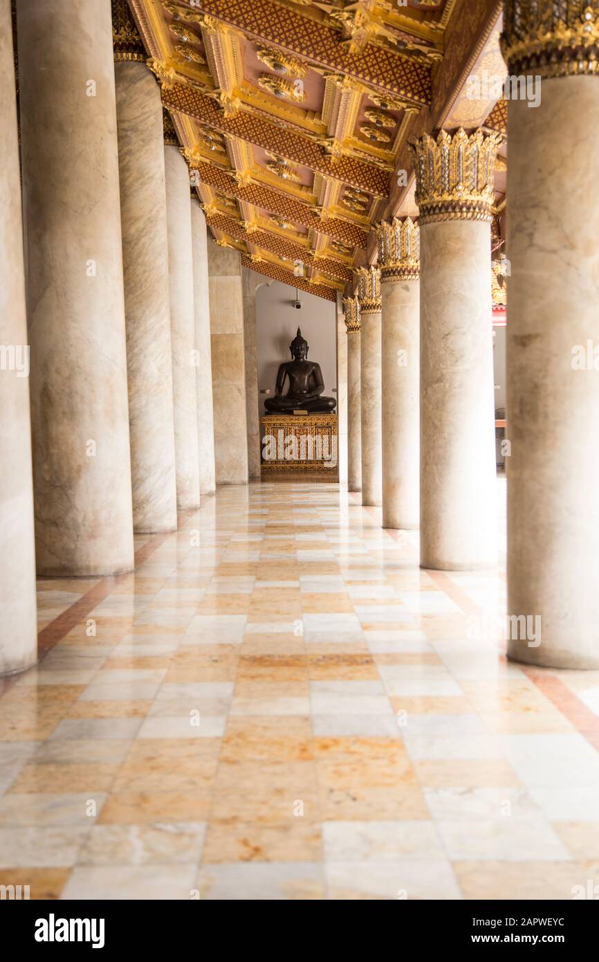 Statua di buddha nero alla fine del corridoio con colonne di marmo. Foto Stock
