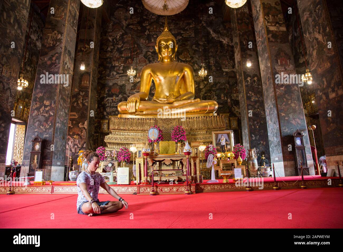 Uomo con un cucciolo meditato al tempio Wat Suthat Thepwararam Foto Stock