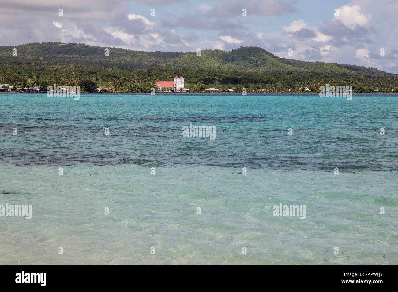 Vista di una chiesa lontana attraverso un mare turchese, Samoa Foto Stock