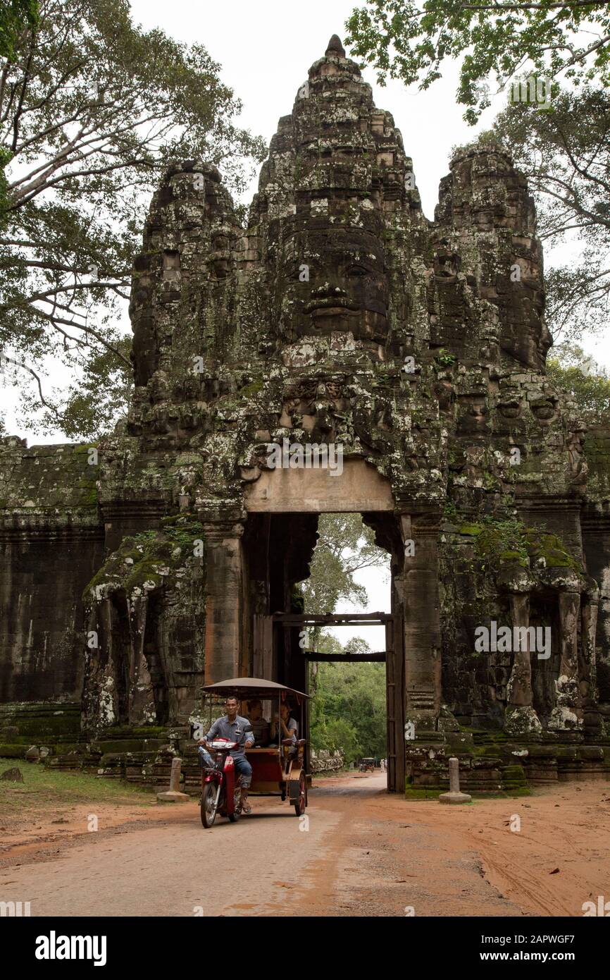 Tuk tuk e porta antica con tre facce umane scolpite sulle rocce Foto Stock