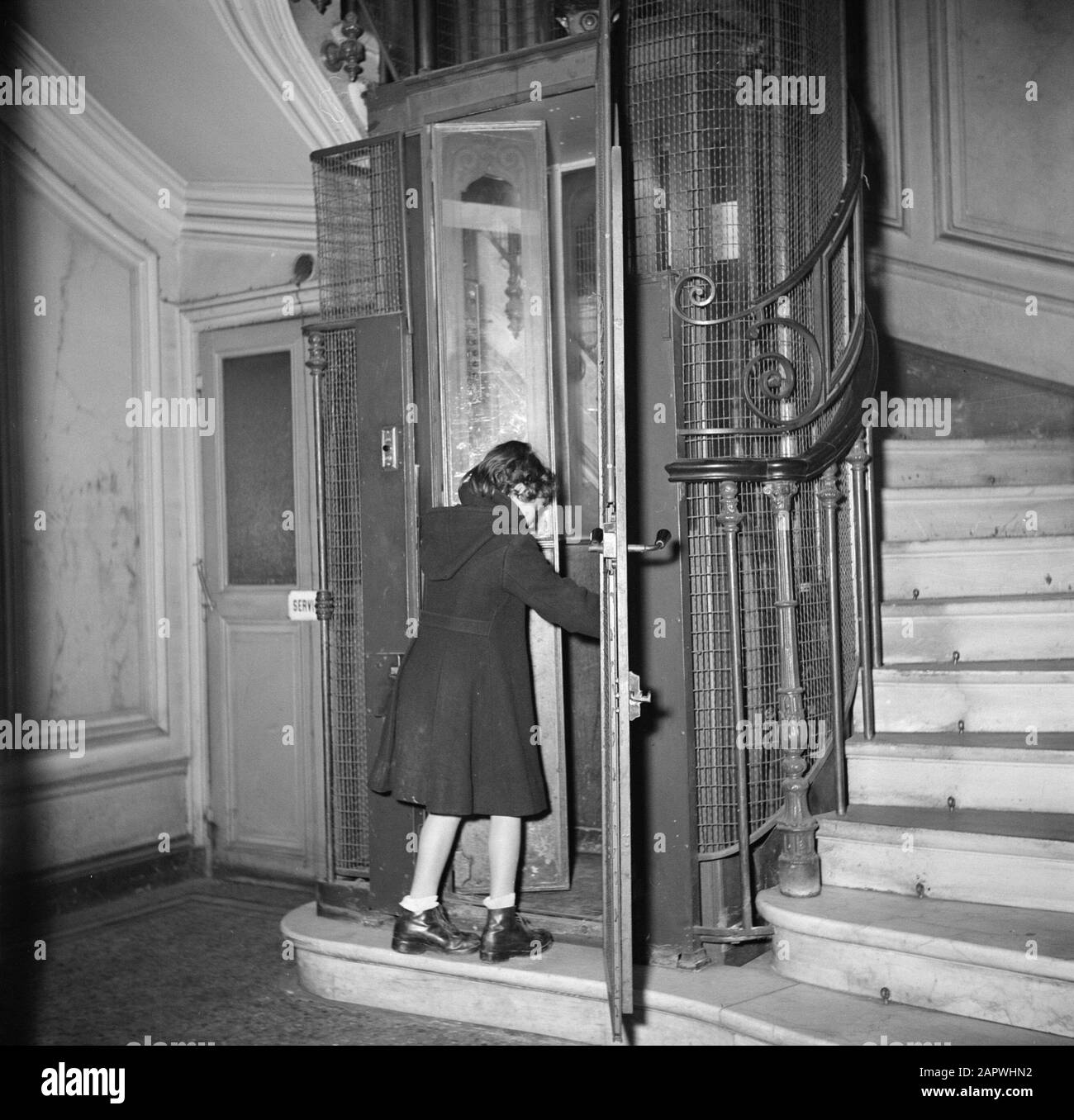 Residenti di un edificio di appartamenti a Paris Girl entra in ascensore Data: 1950 luogo: Francia, Parigi Parole Chiave: Ascensori, ragazze, scale Foto Stock