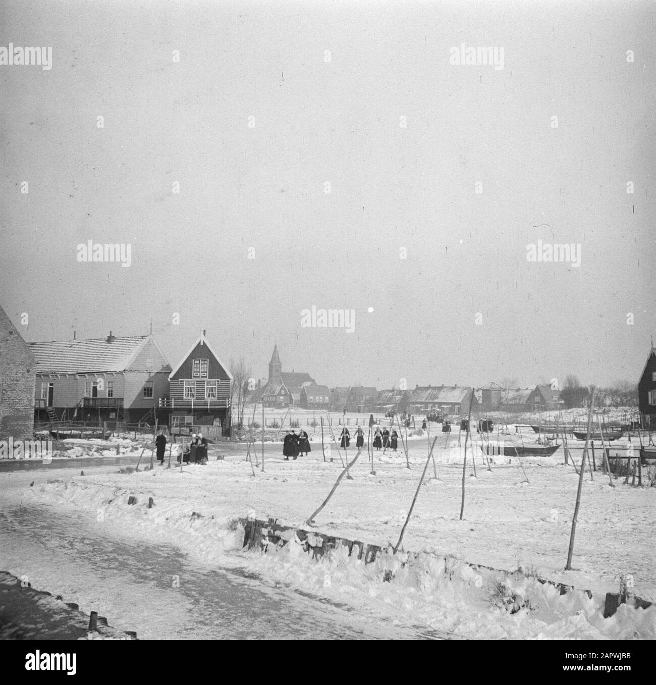 Matrimonio sul ghiaccio In Marken Persone in costume tradizionale camminando attraverso la neve lungo una fila di case Data: 1 febbraio 1947 posizione: Marken, Noord-Holland Parole Chiave: Ghiaccio, edifici della chiesa, costi tradizionali, neve, alloggio Foto Stock