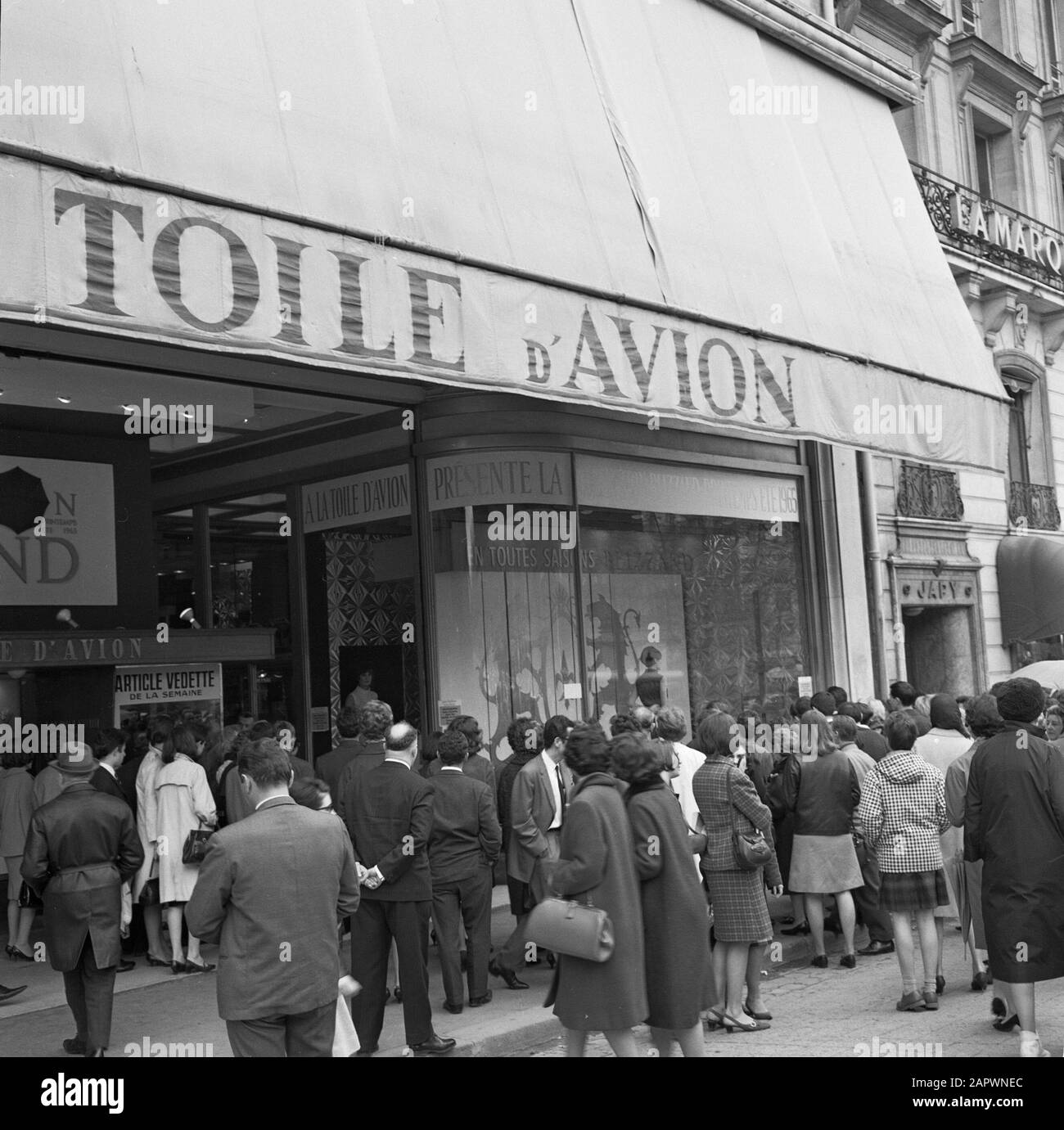 Pariser Bilder [la vita di strada di Parigi] Fashion show of rainwear nella finestra di 'la Toile d'Avion' attira l'attenzione del pubblico sugli Champs-Elysées Data: 1965 luogo: Francia, Parigi Parole Chiave: Vetrine, abbigliamento, sfilate di moda, immagini di strada, negozi Foto Stock