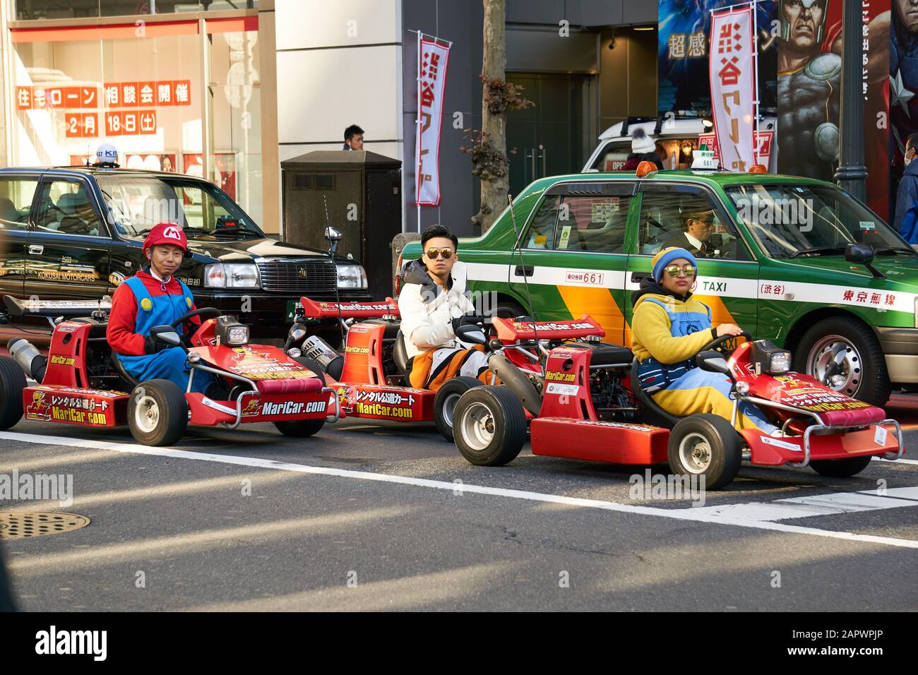 Persone giapponesi vestite da Mario, un minion, e altri personaggi, in sella a un carro o a un'auto MariCar (maricar.com) per le strade di Shibuya. Foto Stock