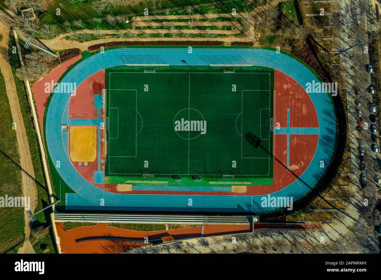Veduta aerea dall'alto verso il basso di un complesso sportivo multi-funzionale con pista e campo blu, campo da calcio verde e stand in Almansa Spagna Foto Stock