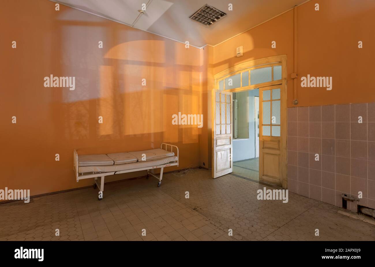 Sagome e ombre dalla finestra sulla parete della stanza con un letto di ospedale in un ospedale abbandonato, di notte Foto Stock