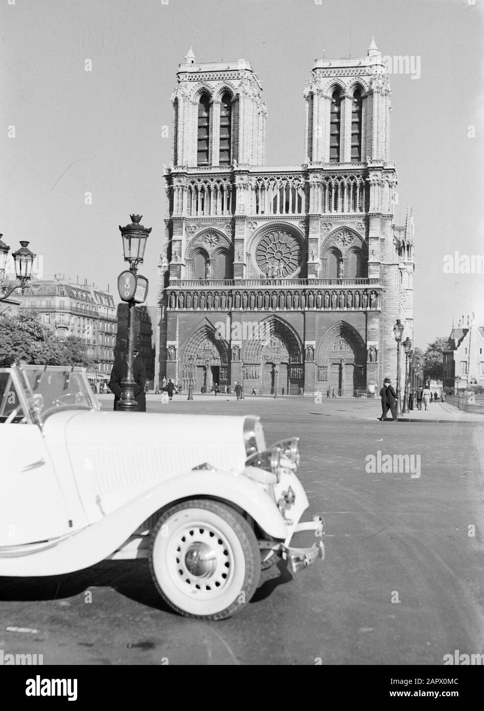Reportage Parigi Parigi. West façade della Cattedrale di Notre Dame con un'auto per passeggeri e luci di strada in primo piano Data: 1937 posizione: Francia, Parigi Parole Chiave: Architettura, auto, gotico, cattedrali, torri della chiesa, sculture di strada, mobili di strada, illuminazione di strada Foto Stock