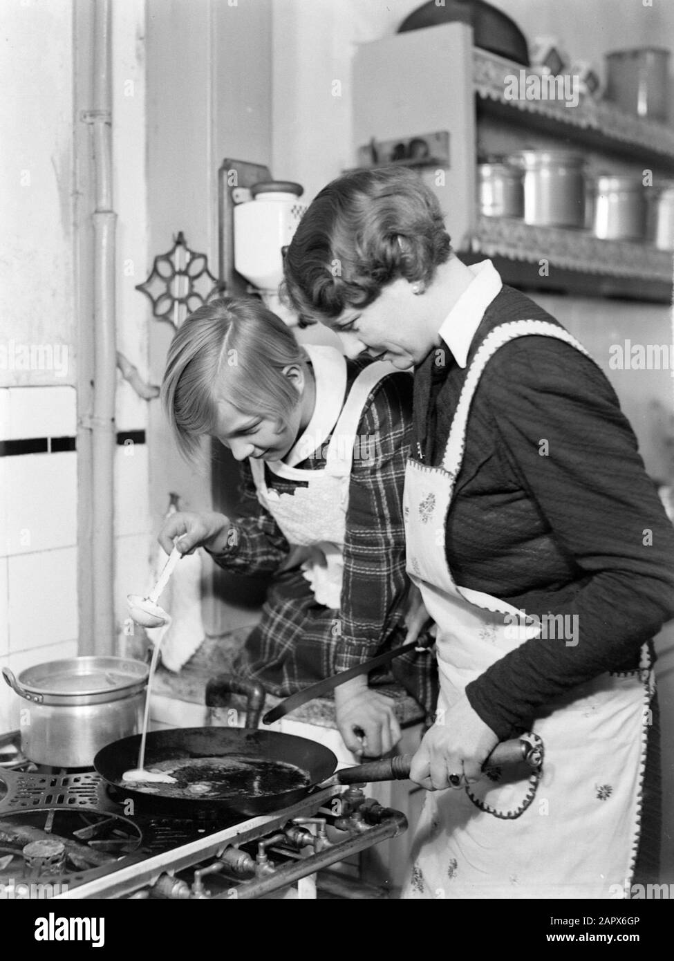 Foto di famiglia Renée si versa con un cucchiaio di pastella in una padella tenuta da nell Langlais sulla stufa a gas Annotazione: Figlia di nell Langlais la seconda moglie di Guglielmo del poll Data: 1931 Parole Chiave: Cucine, cucina, preparazione alimentare Nome personale: Langlais, nell Foto Stock