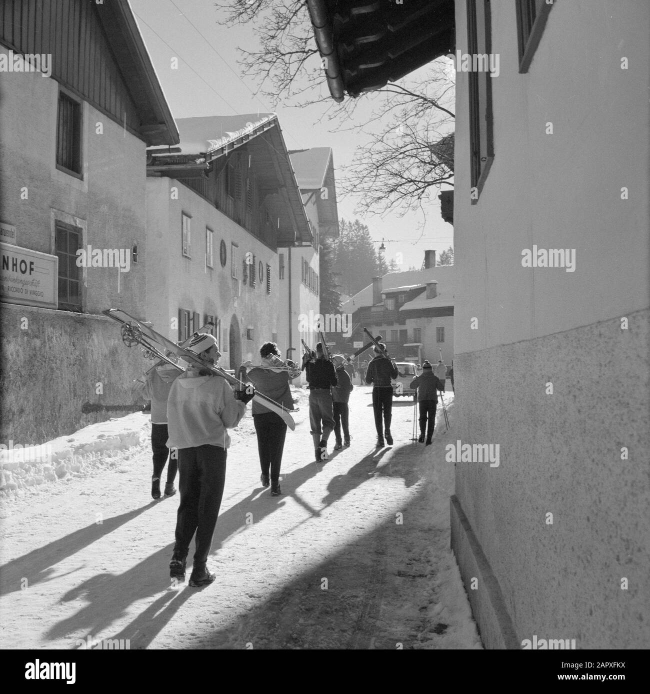 Inverno In Tirolo Sciatori a piedi attraverso Igls Data: Gennaio 1960 Località: Igls, Austria, Tirolo Parole Chiave: Montagne, villaggi, sci, neve, inverno, sport invernali, case Foto Stock