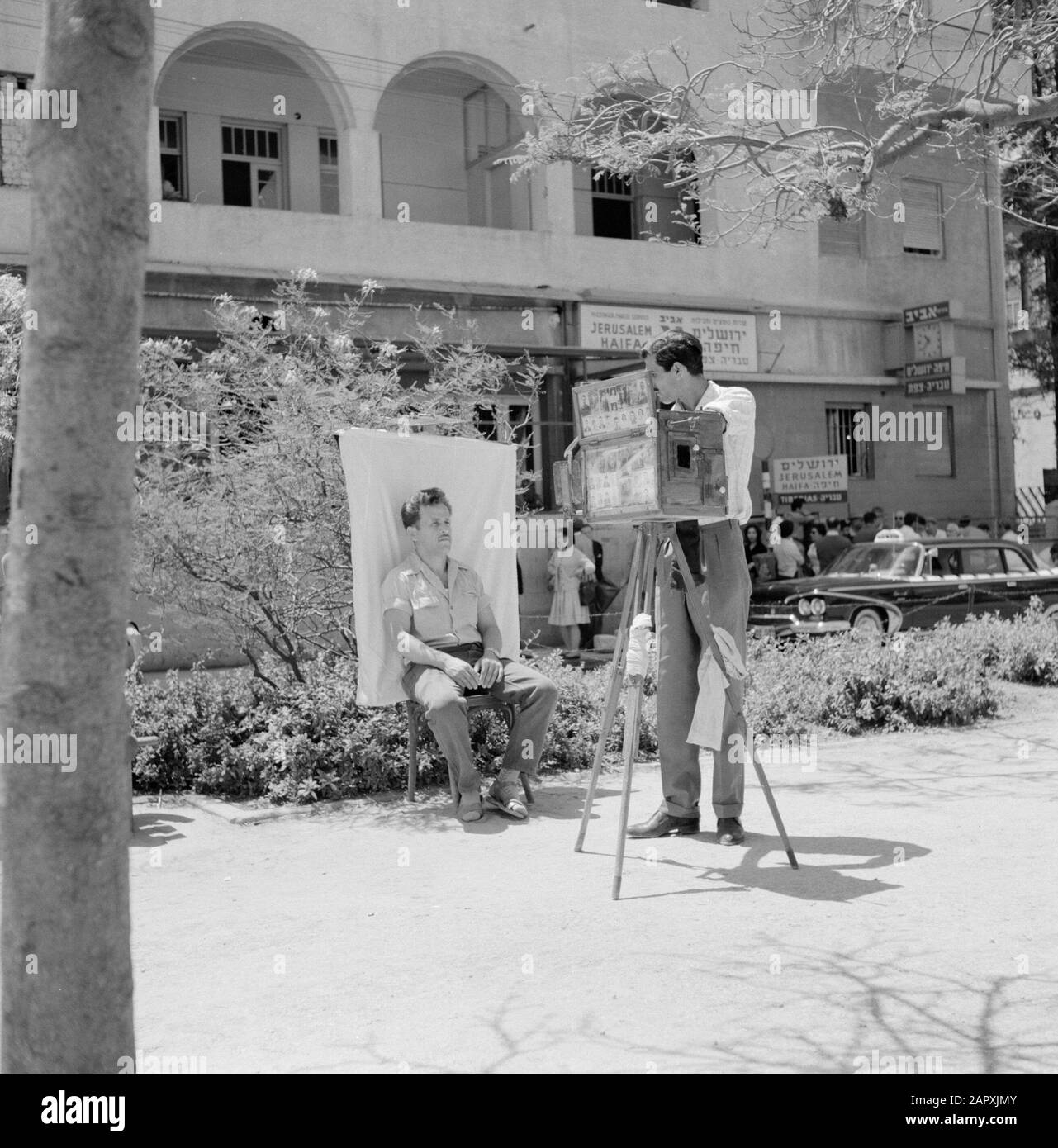 Israele 1964-1965: Tel Aviv, Rothschild Boulevard Street fotografo sta facendo un ritratto di un giovane uomo Annotazione: Per creare uno 'studio all'aperto' il fotografo usa una tela bianca di sfondo Data: 1964 Località: Israele, Tel Aviv Parole Chiave: Tela di sfondo, foto, attrezzature fotografiche, fotografi, ritratti, immagini di strada Foto Stock