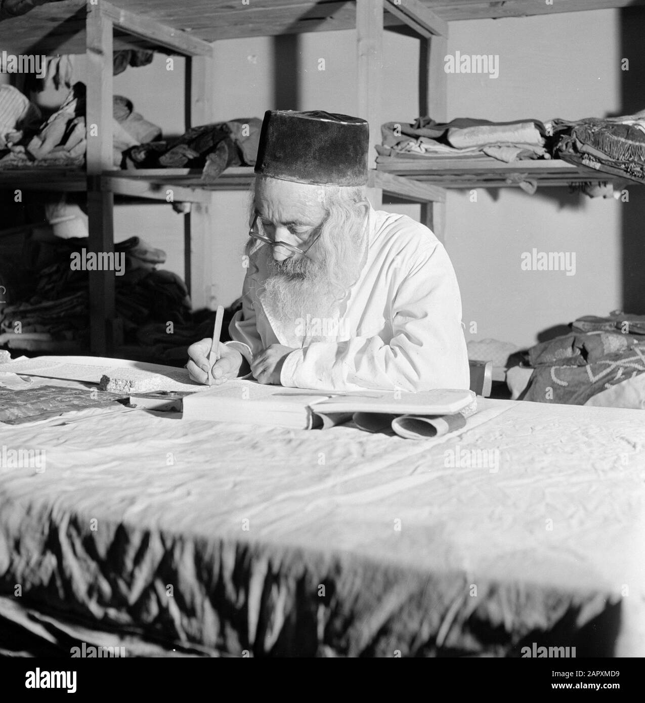 Israele 1964-1965: Gerusalemme (Gerusalemme), Thorarrolls Torah scrittore al lavoro dietro un tavolo da lavoro Annotazione: La Torah (la Legge Mosaica) è scritto su un rotolo, che è fatto di pergamena dalla pelle di un animale kosher. Le diverse parti della pergamena sono fissate l'una all'altra con un tendine, e il testo è scritto a mano. L'inchiostro è spesso prodotto da solo e deve soddisfare determinati requisiti. Infine, il rotolo è attaccato a due bastoni di legno con manici ed entrambe le estremità sono rotolate verso la metà Data: 1964 luogo: Israele, Gerusalemme Parole Chiave: Torah, scrittura a mano, religione ebraica, scrittori, lavoro Foto Stock