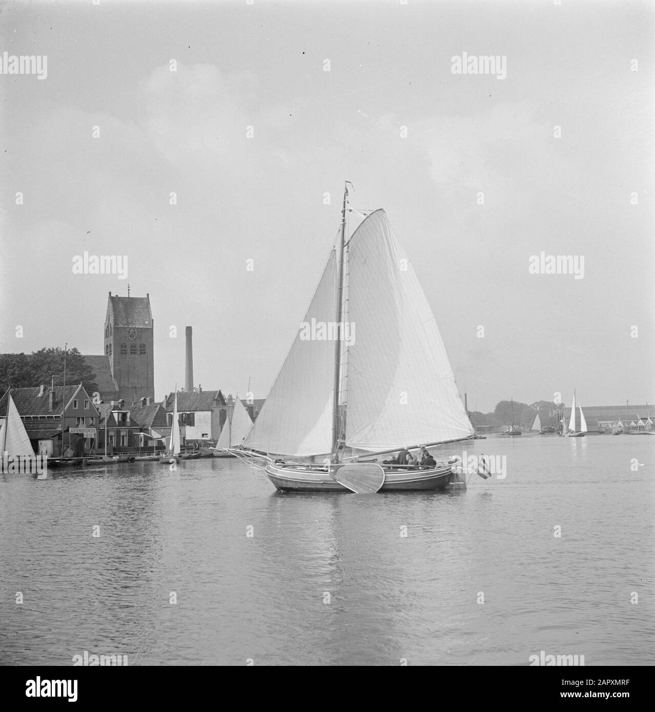Friesland Tjalk con in background il villaggio Grouw Data: 1 gennaio 1932 posizione: Friesland, Grouw Parole Chiave: Torri della Chiesa, laghi, navi a vela Foto Stock