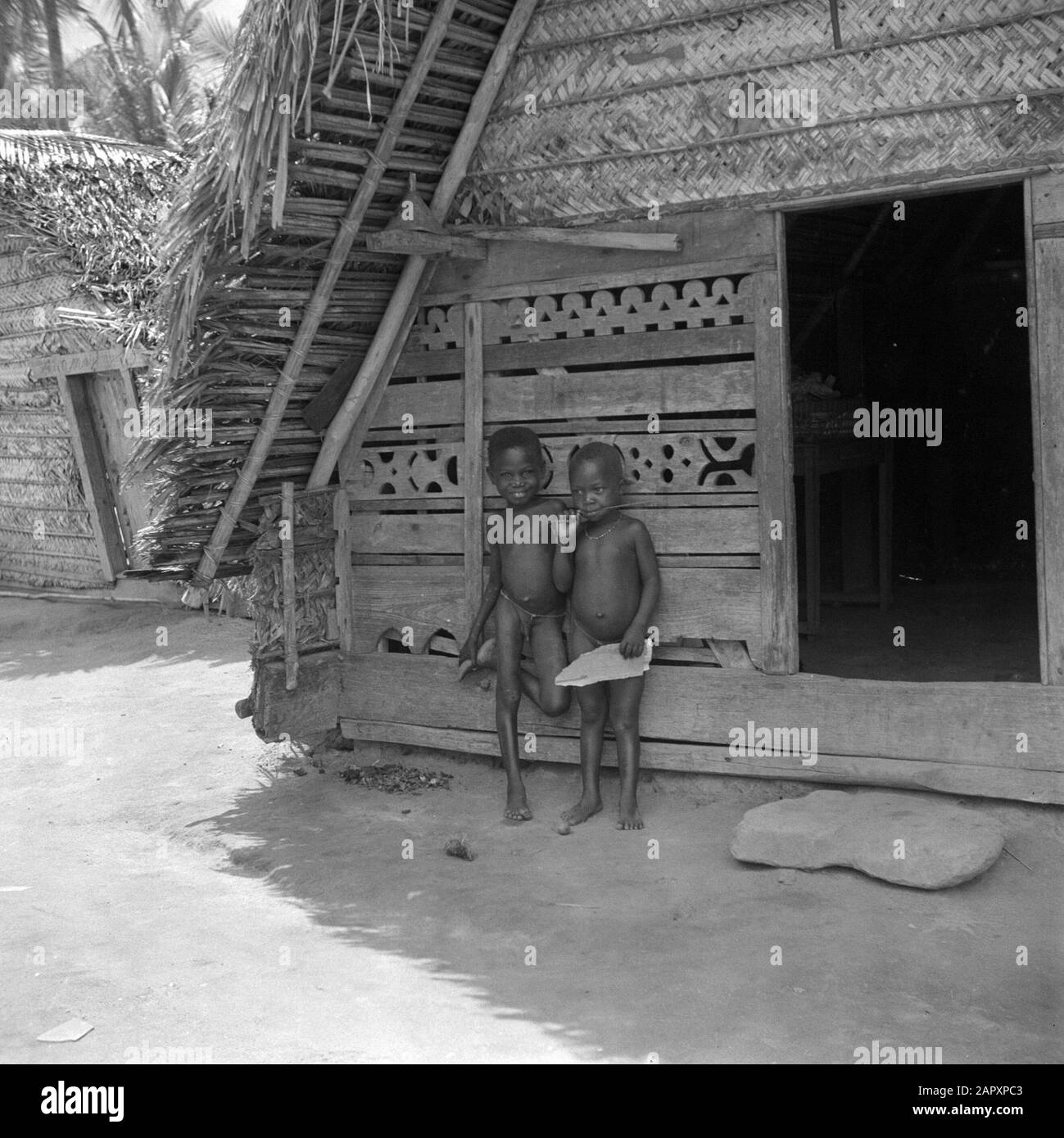 Viaggio nel Suriname e nelle Antille Olandesi Due bambini per una fattoria forestale, decorata con sculture in legno Data: 1947 luogo: Suriname Parole Chiave: Popolazione indigena, bambini, case Foto Stock