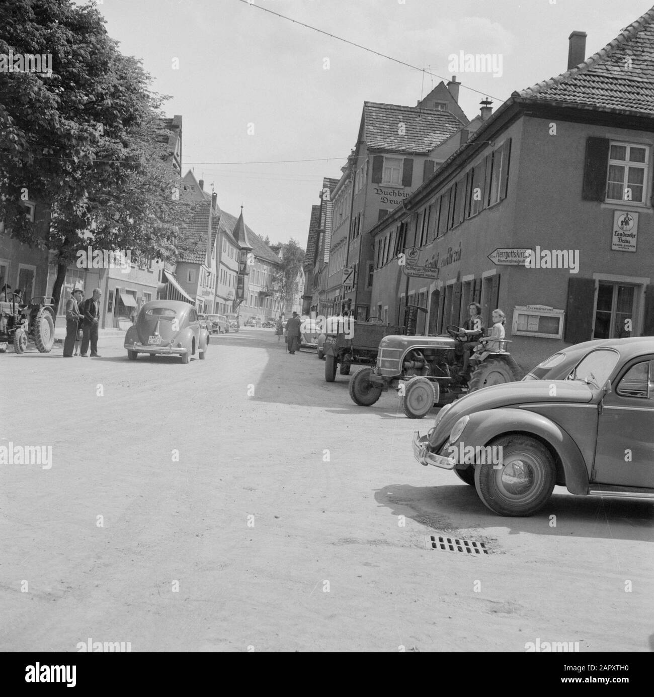 Hohenloher Land Traffic in una strada a Cregingen con all'angolo della casa un cartello per il Herrgottskirche con l'altare Riemenschneider Data: Non data: Luogo: Baden-Württemberg, Cregingen, Germania, Germania Ovest parole Chiave: Automobili, sculture di strada, mobili di strada, trattori, negozi Foto Stock