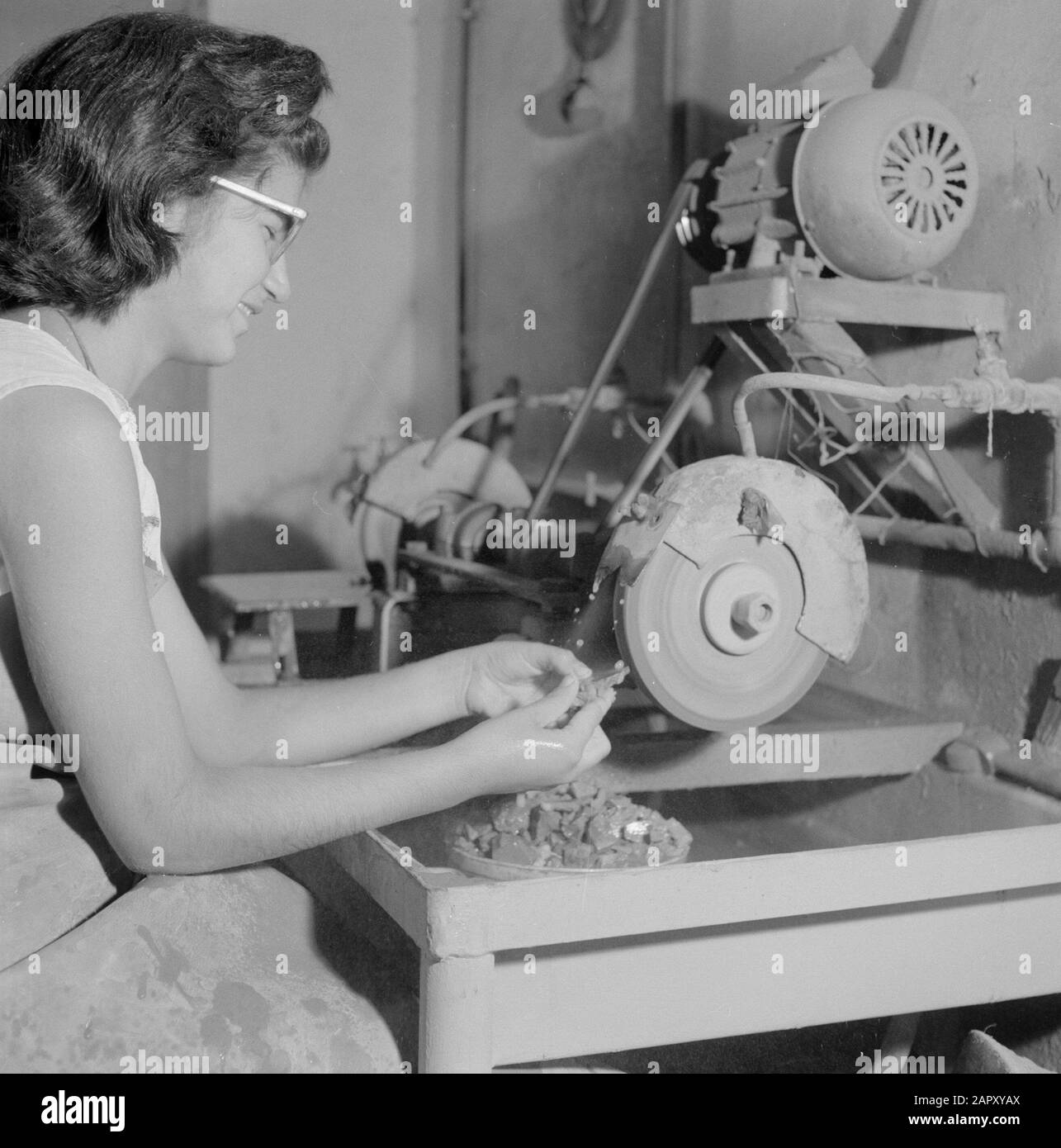Israele - Eilat Woman lavorando alla macinazione della pietra Eilat in un'azienda in cui questa pietra viene lavorata e lavorata. Data: 1 gennaio 1963 luogo: Eilat, Israele Parole Chiave: Operai, gemme, attrezzi, pietre semipreziose, industria, macchine, smerigliatrici Foto Stock