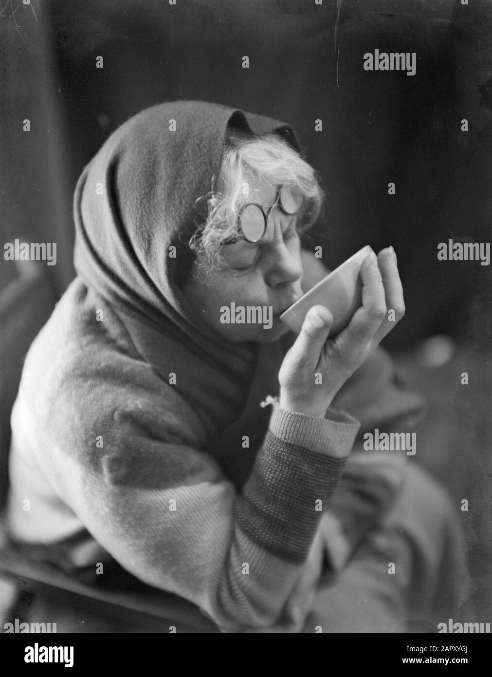 Pubblicità fotografia Donna con un panno o sciarpa battuto intorno alla testa, bevande una tazza di caffè Data: 1 gennaio 1932 Parole Chiave: Caffè, stoviglie Foto Stock