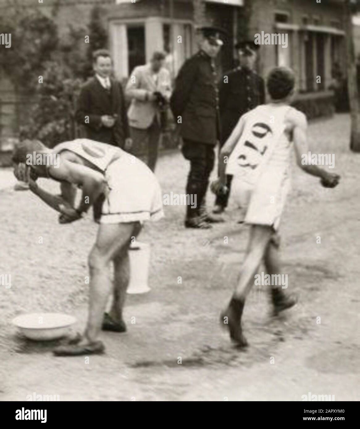 Due canadesi si rinfrescheranno con acqua da una ciotola a terra durante la maratona alle Olimpiadi di Amsterdam del 1928, nei Paesi Bassi. Foto Stock