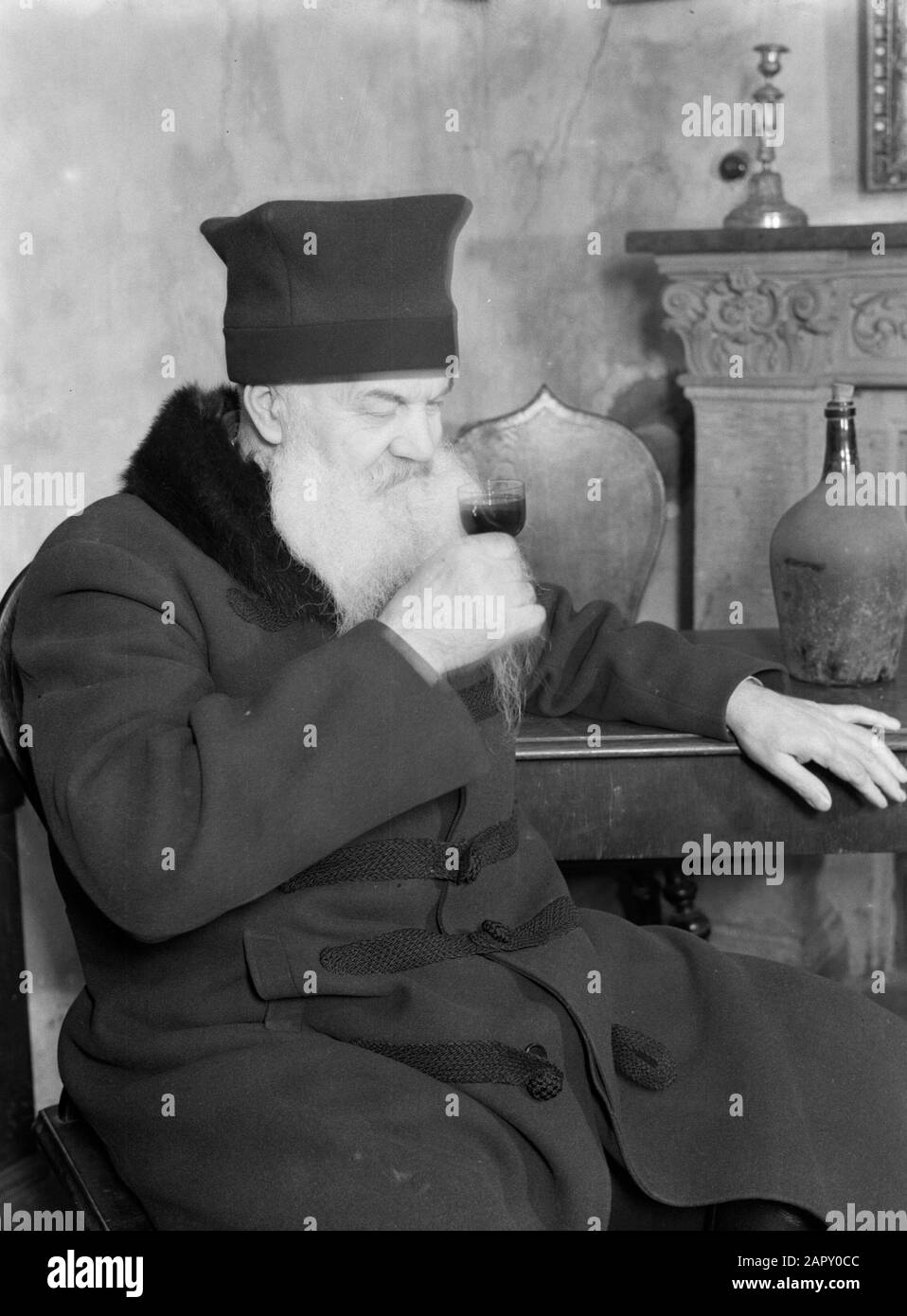 Viaggio In Polonia Varsavia. Porter of Winery Fukier drink un bicchiere di vino Annotazione: I Fukiers erano strettamente collegati con la famiglia bancaria tedesca meridionale Fugger, qualunque nome usassero originariamente. La loro cantina fiorì attraverso i secoli e molte grandi persone della terra la visitarono. Nel 1926, la famiglia vendette l'azienda per un bisogno di soldi. Tuttavia, il nuovo proprietario ha continuato a portare il vecchio nome. L'edificio in cui si trovava la cantina dal 1805 fu perso nel 1944, ma fu ricostruito dopo il 1945 e un ristorante fu fondato sotto il vecchio nome. Data: 1934 Luogo: Polonia, Varsavia Foto Stock