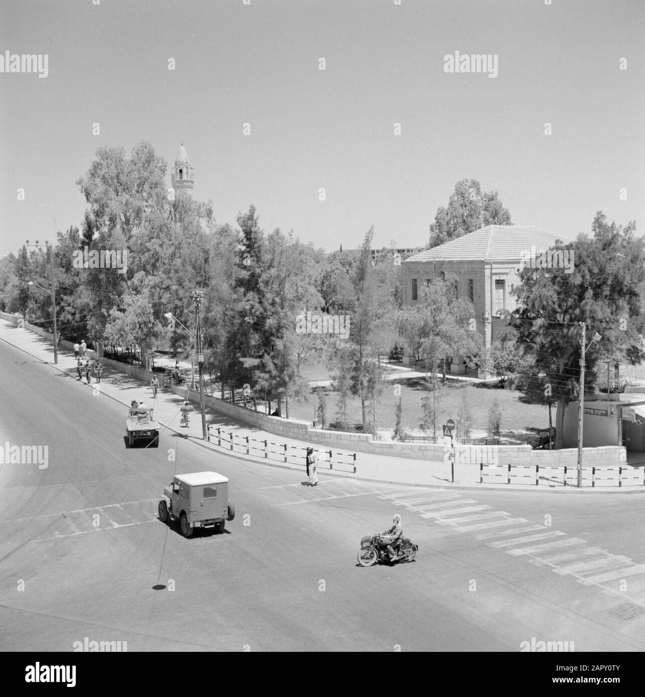 Israele: Bersheba Road con attraversamento, con traffico motorizzato e con pedoni compreso militare. Lungo la strada una casa decente con ampio giardino Data: Non data posizione: Bersceba, Israele Parole Chiave: Militare, moto, statue di strada, giardini, segnaletica stradale, mezzi di trasporto, ville Foto Stock