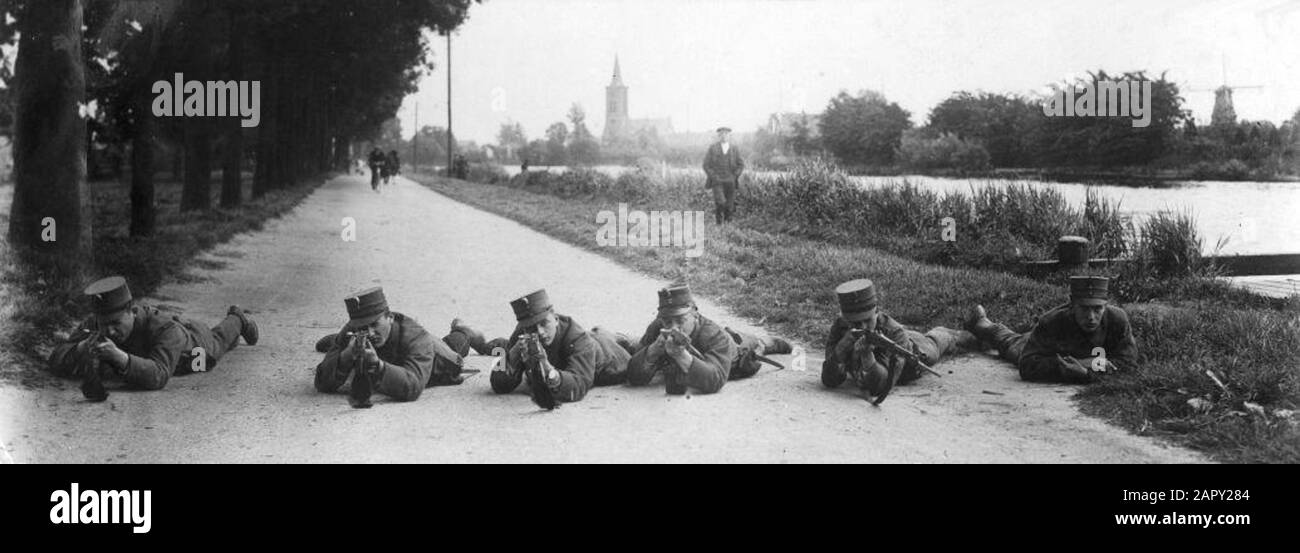 Prima guerra mondiale, Paesi Bassi. Esercizio militare ad Amsterdam, 1916, sei soldati sdraiati sulla strada con il fucile in attacco. Si trovano lungo un canale. Una torre della chiesa sullo sfondo. Foto Stock