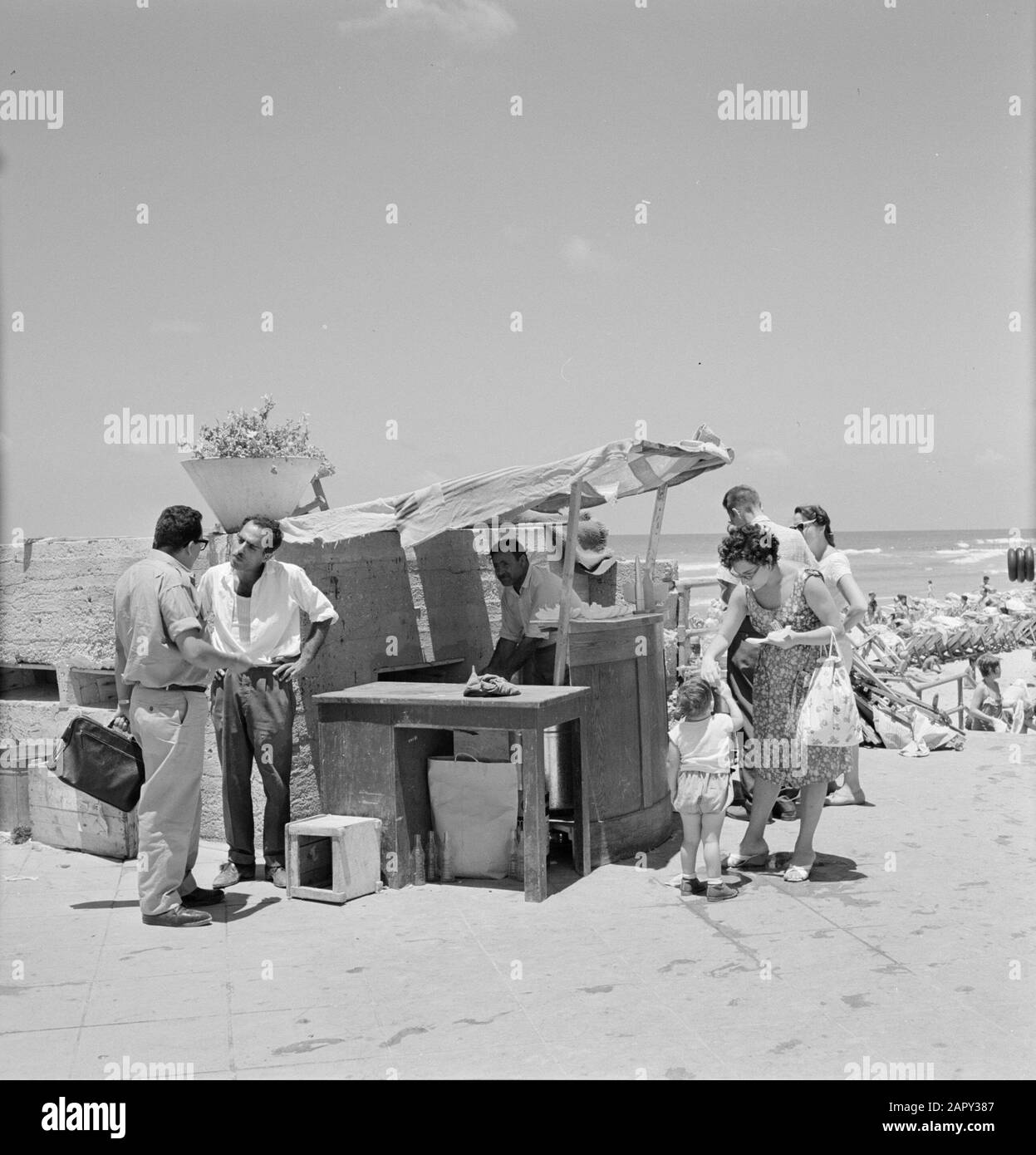 Israele 1964-1965: Tel Aviv, il Sabbath al mare la gente vestito Summerly mangia melone sul bordo della spiaggia ad una semplice stalla Annotazione: Durante il Sabbath molte persone da Tel Aviv al mare Data: 1964 luogo: Israele, Tel Aviv Parole Chiave: Bagnanti, vita quotidiana, frutta, conversazioni, bancarelle, spiagge Foto Stock