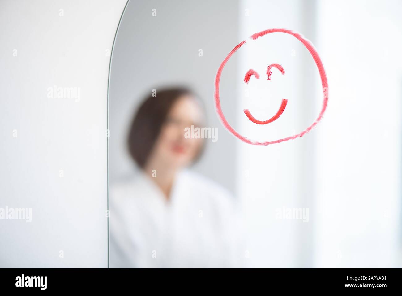 Faccia con sorriso disegnato da rossetto rosso sullo specchio sullo sfondo della donna Foto Stock