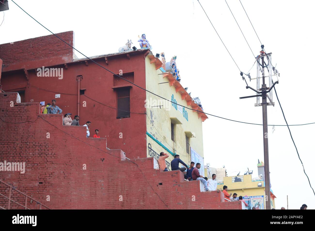 La gente è seduta sulla scala accanto al tempio del ghat del fiume Ganga Foto Stock