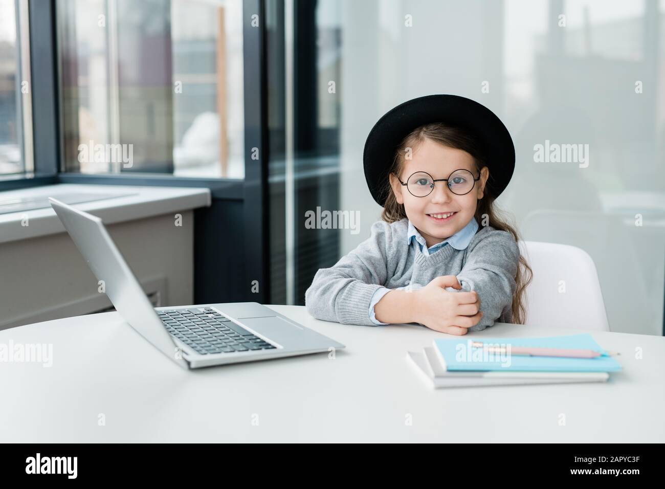 Scholgirl sorridente cute in occhiali e casualwear preparazione di lavoro Foto Stock