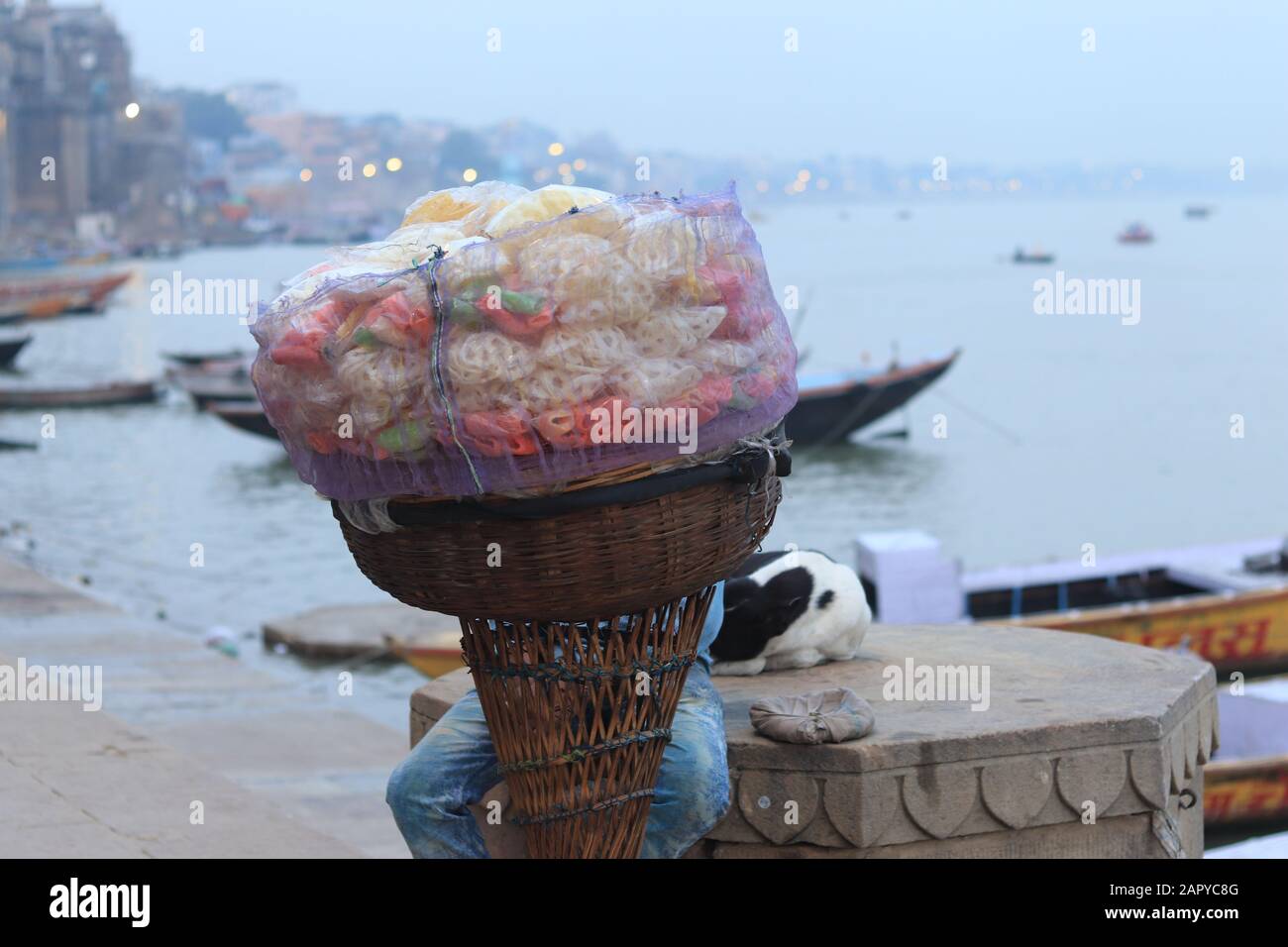 Il venditore indiano di snack è seduto dietro il grande cesto Foto Stock