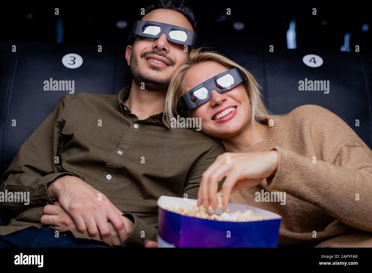 Felice giovane coppia amorosa in occhiali 3d guardando interessante film d'azione Foto Stock