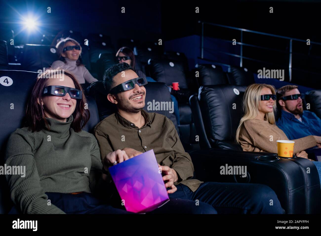 Due coppie giovani felici che hanno popcorn e guardare film attraverso occhiali 3d Foto Stock