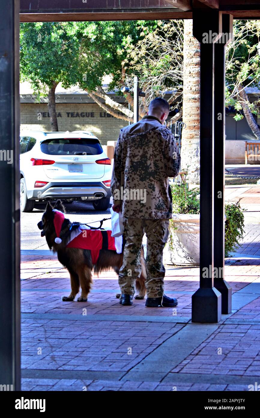 Glendale, STATI UNITI - 14 dicembre 2019: Un soldatino solitario in piedi su un marciapiede con il suo cane. Foto Stock