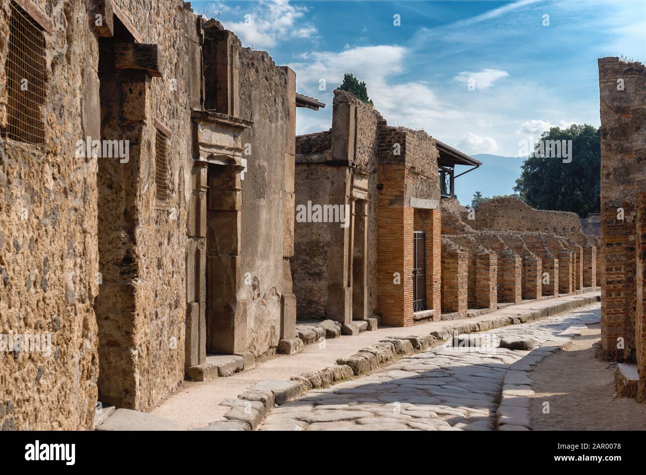 Una strada tra le antiche rovine di pompei, città distrutta dall'eruzione del vulcano vesuvio in Italia, sito iscritto nel patrimonio mondiale dell'UNESCO Foto Stock